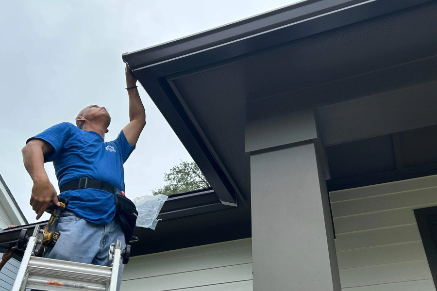 man with tools inspectioning roof gutter for repair service jacksonville fl